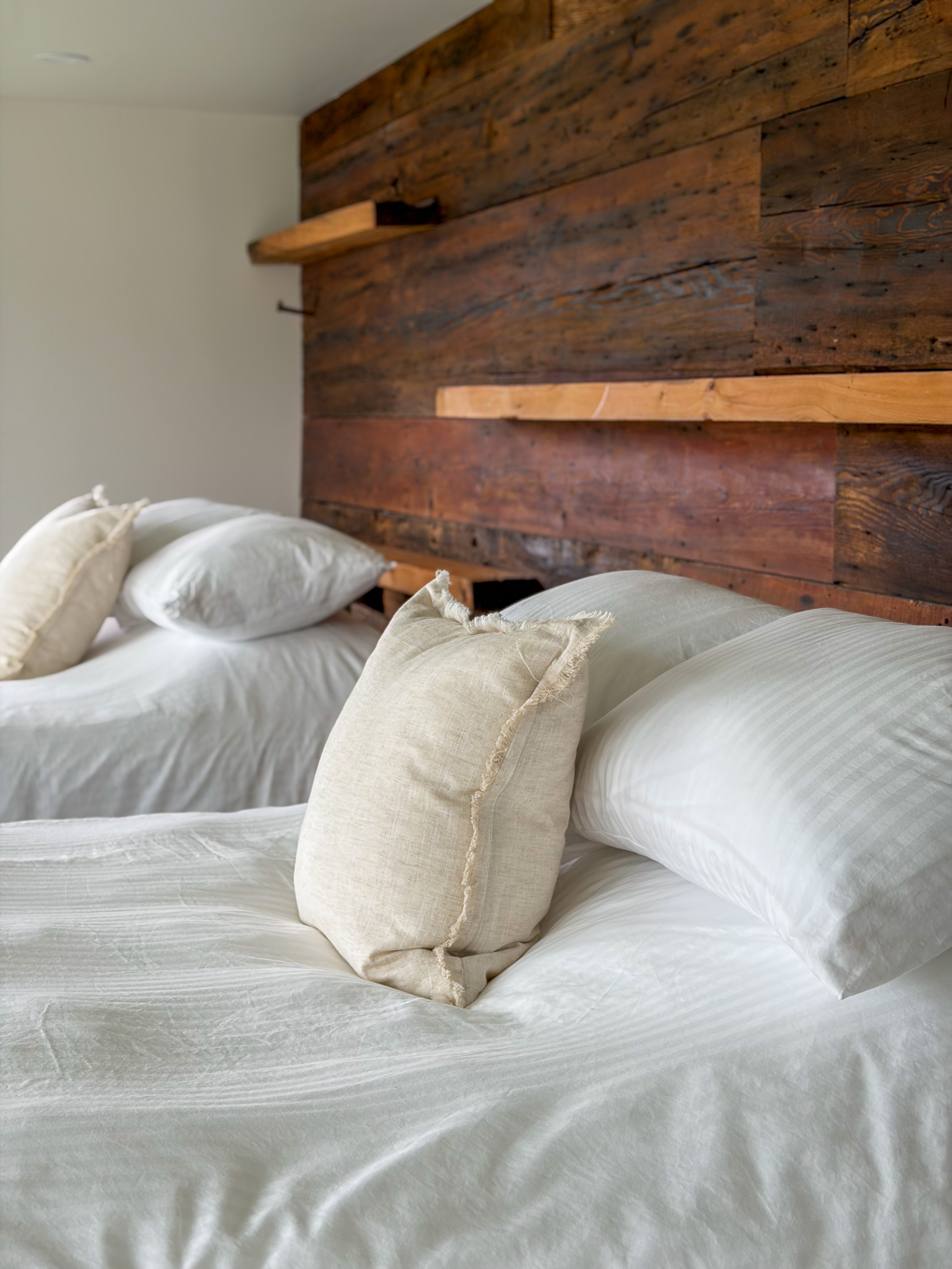 A bedroom with a white bed and barn wood wall at Le Nordik Réserve Boréale