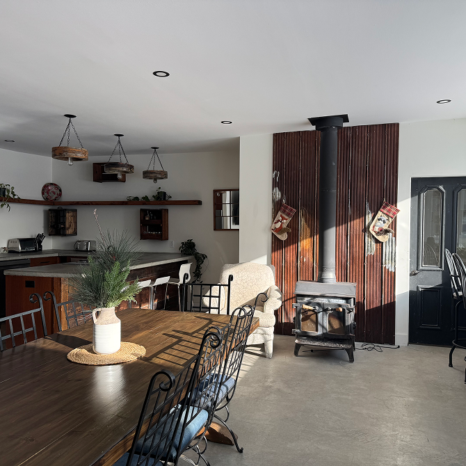 A dining room with a wood stove and a reclaimed wood wall