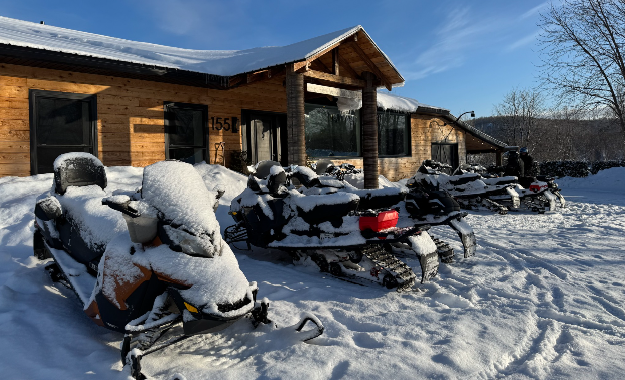 Snow-covered snowmobiles parked in front of a building on the estate in winter