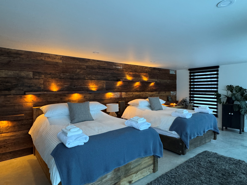 A bedroom with two single beds and a wooden headboard